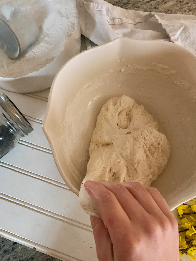 Hand Kneading sourdough bread on white beadboard